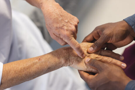 Midsection of african american male doctor examining hands of senior female caucasian patient. Hospital, work, medicine and healthcare.